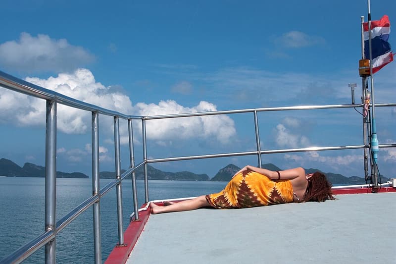 A passenger sunbathing on the deck of a boat among the islands of Ang Thong