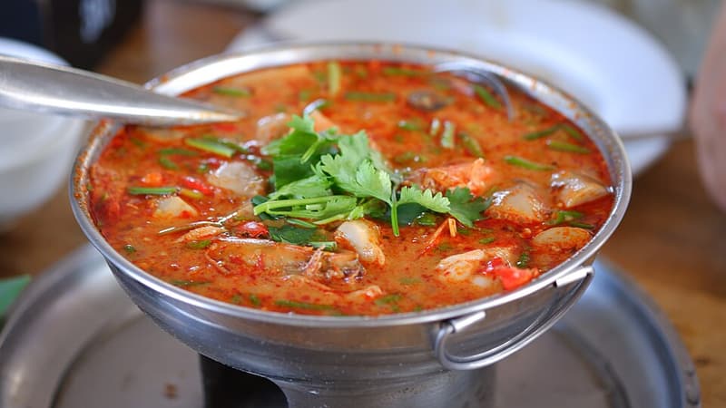 A bowl of tom yum goong soup with prawns and fresh herbs